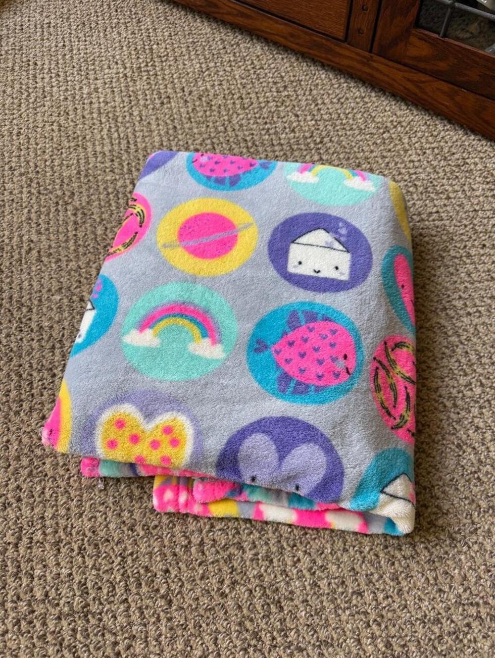 Multi-colored blanket with cartoon icons like food items and rainbows